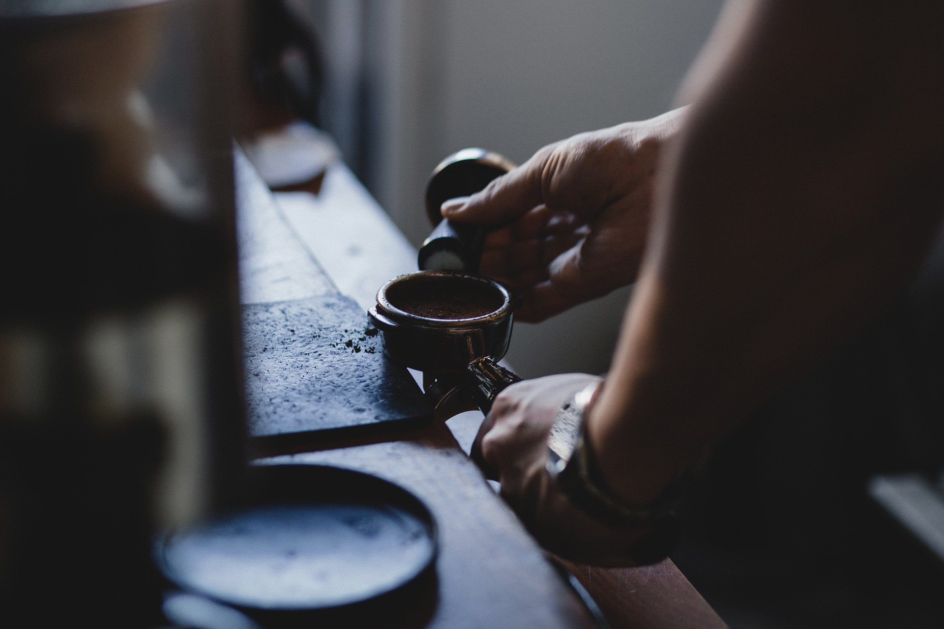 Kuvituskuva: Kädet, jotka laittavat kahvia espressokoneen suodattimeen.