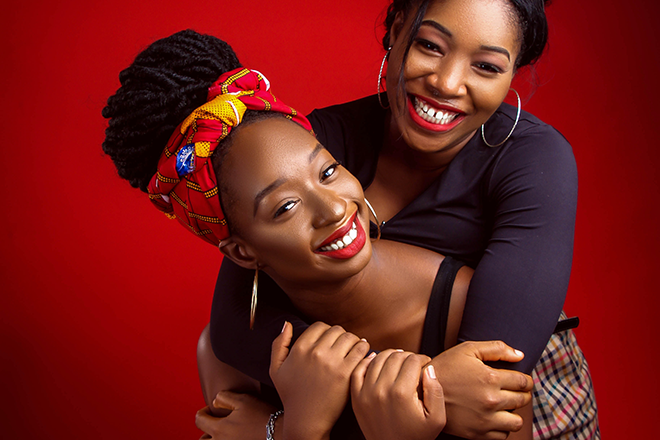 Kuvituskuva: kaksi naista hymyilee kuvassa punaisella taustalla